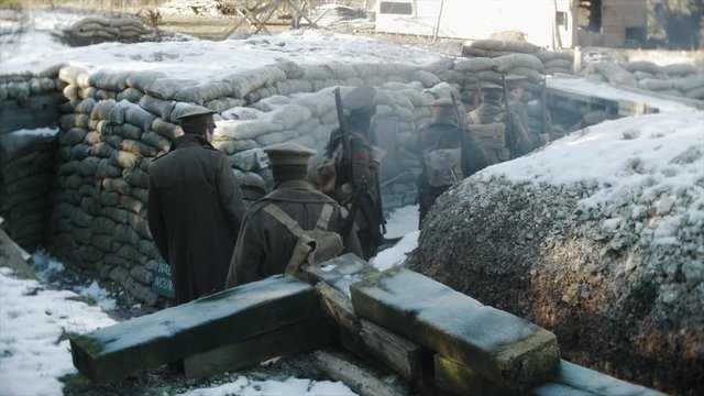 A snow covered First World War tench, cold British WW1 army soldiers walk back from the front line in France.