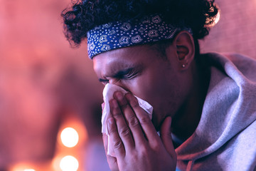 Close portrait of young man of African descent with napkin near his face on the blurred background.