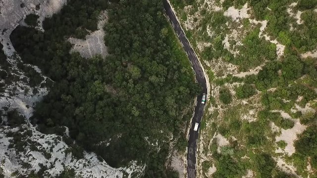 2 Cars sneaking on a mountain pass. Filmed from top bird's eye view with a drone circling around them smoothly. Like in GTA . Summer atmosphere in green forrest und grey rocky french alps landscape