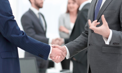 Business partners handshaking over business objects on workplace