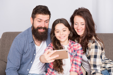 Happy family at home. Little girl use smartphone with mother and father. Family with happy mood. Happy family selfie. bearded man and woman with daughter child. Happy family. Capturing bright moments