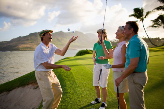 Male golfer smoking a cigar juggles golf balls for his friends as they take a break together.