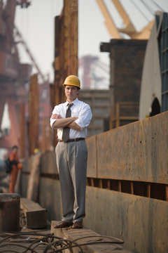 Young adult businessman walking along a shipping dock.