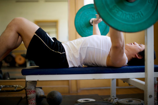 Young adult man lifting weights on a bench press.