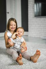 sister is messing with her younger brother. Sister is holding a little brother. Siblings.