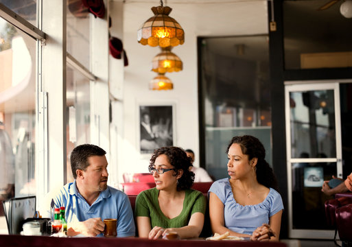 Group of friends talking over coffee in a diner.