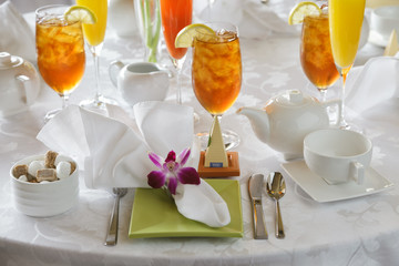 Elegant afternoon tea service with iced tea in glasses setting on white linen table cloth