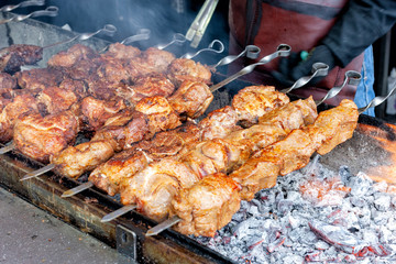 grilled meat at street festival. huge pieces of meat cooking at barbeque with coal and fire.