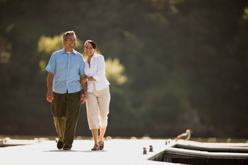 Husband and wife walking along a wharf linking arms