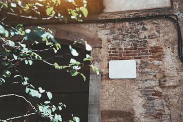 Marble house nameplate mockup on the corner of an antique building in Barcelona, Spain: empty white space for number and text with street name on flaked brick and stone wall near the arch of a window