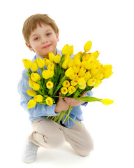 Little boy with a bouquet of flowers tulips.