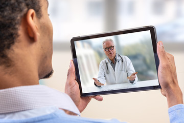 virtual live chat with the patient with digital tablet and a doctor via internet. In-home care for a young male patient in telemedicine or telehealth,