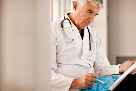 Male doctor reading notes in someones file.