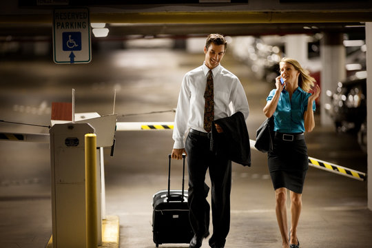 Two business colleagues walking through an underground parking lot.