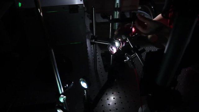 Photonics lab experimentation. Experiment with photonics equipment. Photonics test with lenses. Setting up lab equipment for photonics experiment. Experiment with light and lenses.