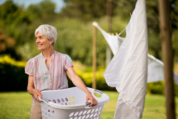 Happy senior woman hanging laundry on a clothes line.