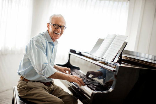 Smiling senior man happily playing the piano.