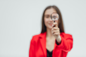 Funny expressions. Shocked woman looking at magnifying glass. A surprised girl looks at opening the keys with big eyes through a magnifying glass, isolated on a white background.