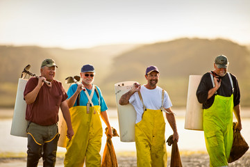 Group of fisherman on the beach with bags of shellfish.