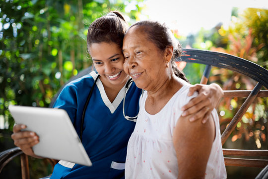 Young doctor using digital tablet with grandmother.