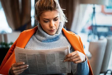 Foto op Canvas Young businesswoman reading daily newspaper in a cafe. © Drazen