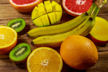 Assortment of tropical fruits on wooden table. Still life with bananas, mango, oranges, grapefruit and kiwi fruits