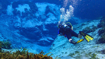 Man scuba diving in a spring in florida in the crystal clear blue water.