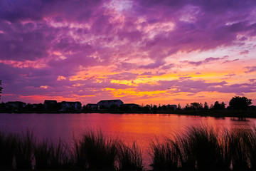 Purple, pink, yellow and red cloudy sunset over a lake.