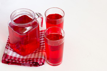 Fruit and berry red juice in glasses and jug on a white background. Fresh and cold summer drink.