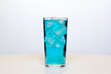 Glass with a blue cocktail with ice on a white background. © Elena