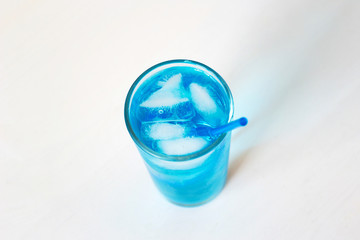 Glass with a blue cocktail with ice on a white background.