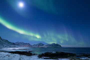 Beautiful northern lights over the snow covered winter landscape of the Lofoten islands