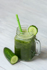 Healthy green smoothie with ingredients on white wooden background