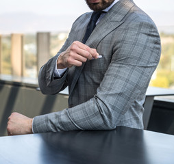 Man in expensive custom tailored suit standing and posing outdoors on balcony