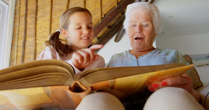 Low angle view of Caucasian Grandmother and granddaughter looking at photo album 4k
