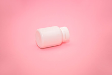 White jar with place for text and pills on pink background. dietary supplements, tablets, vitamins, capsules. The concept of a healthy life.