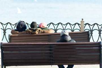 company of people relaxing on the benches against the backdrop of the sea, ocean. love story, broken heart