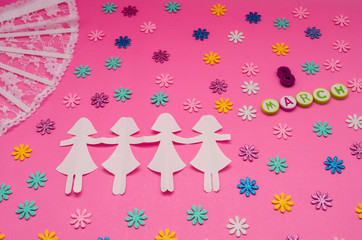 Paper dolls chain, fan and little colorful flowers on pink background. 