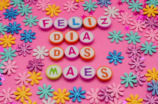 Feliz Dia Das Maes Made From Colorful Letters And Little Colorful Flowers Against Pink Background