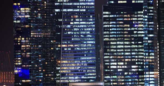 Office glass windows at night on modern skyscrapers in city downtown. Singapore financial district urban architecture