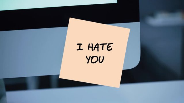 I hate you. The inscription on the sticker on the monitor. Message. Motivation. Reminder. Handwritten text written with a marker. Color sticker. A message for an employee, a colleague