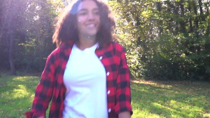 Biracial African American mixed race teenage girl young woman carrying basket of apples past a gray tractor through a sunny apple orchard