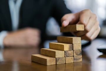 Businessman planing and strategy putting wooden blocks risk or success project hands control stack...