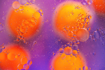 Abstract background. Orange with purple color. Distortions in water with drops of oil. Bright abstraction, ultraviolet. Circles on the water