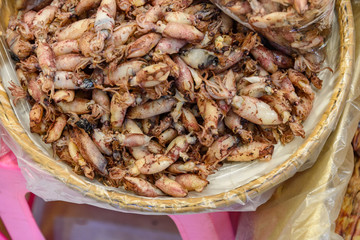 Top view heap of baby squids on the basket are sold in local seafood outdoor seafood market in Thailand.
