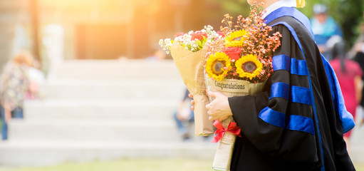 Education theme concept. Graduate holding a hat and flowers.
