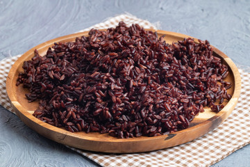 close up riceberry rice on wooden plate