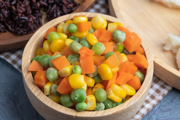carrots corns and peas on wooden bowl