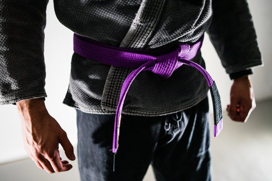 Close Up on Midsection Of A Brazilian Jiu JItsu BJJ fighter with purple belt in a black gi kimono - Powered by Adobe