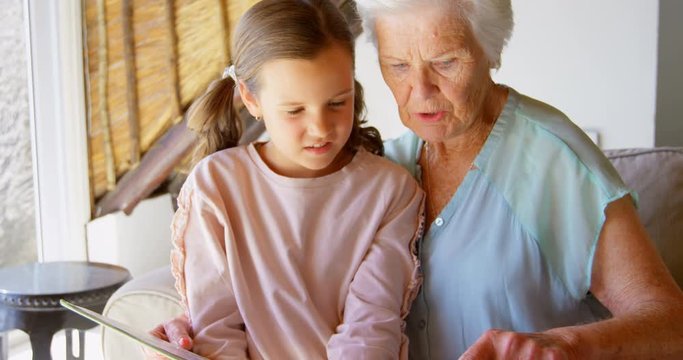 Front view of Caucasian Grandmother and granddaughter looking at photo album 4k